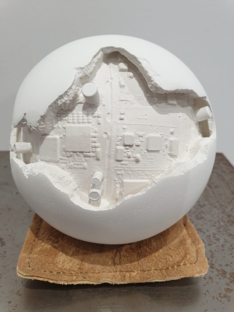 Human AI 1, scultura sferica in gesso eroso con cavità che rivela circuiti elettronici interni, opera di Cristian Bertolotto.