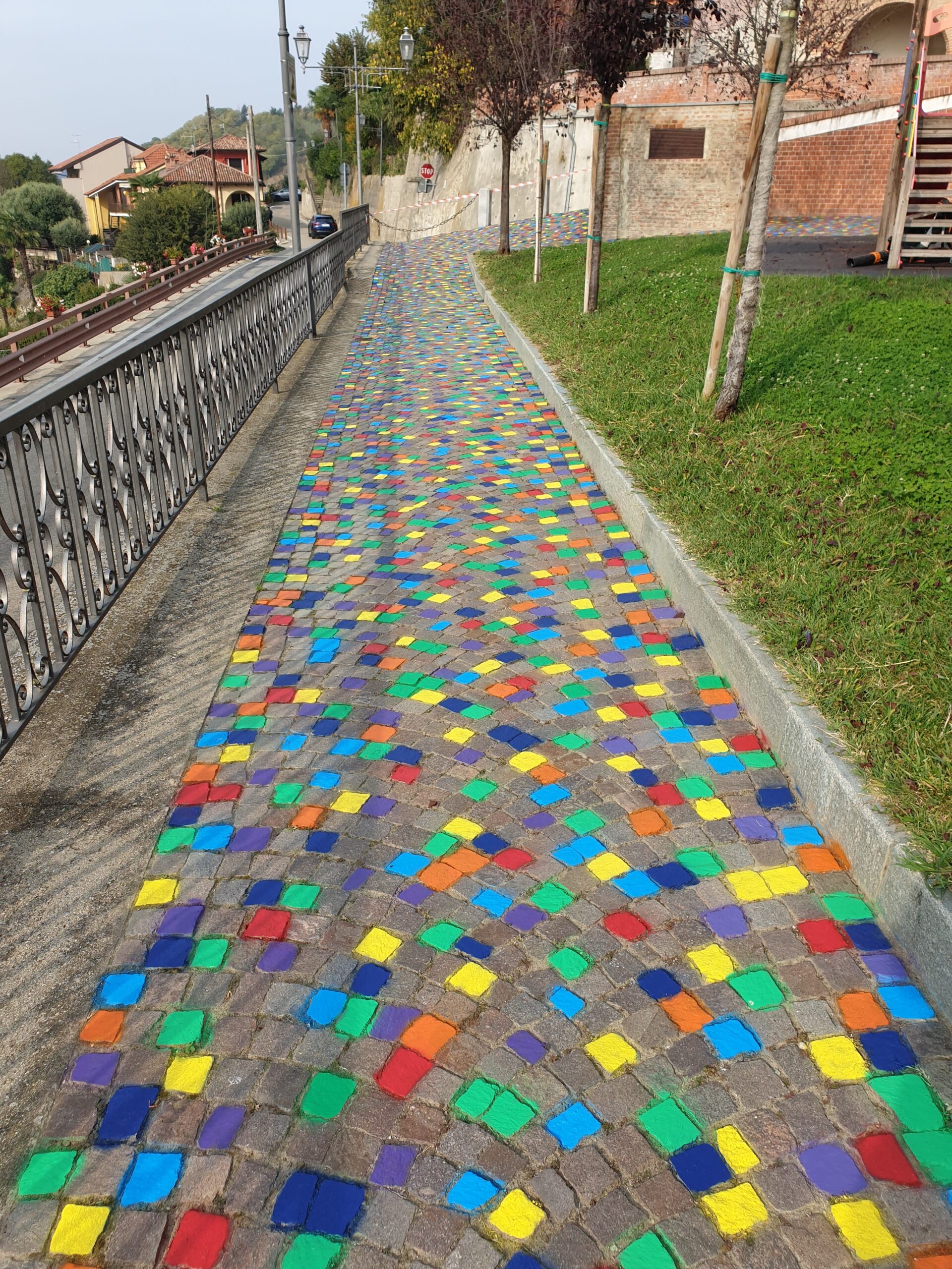 Opera di Land Art “Meditaçion” a Monticello d’Alba (CN), installazione di land art con sanpietrini colorati a spirale, percorso simbolico tra dimensione spirituale e materiale, arte ambientale contemporanea con geometrie circolari e colori vibranti.