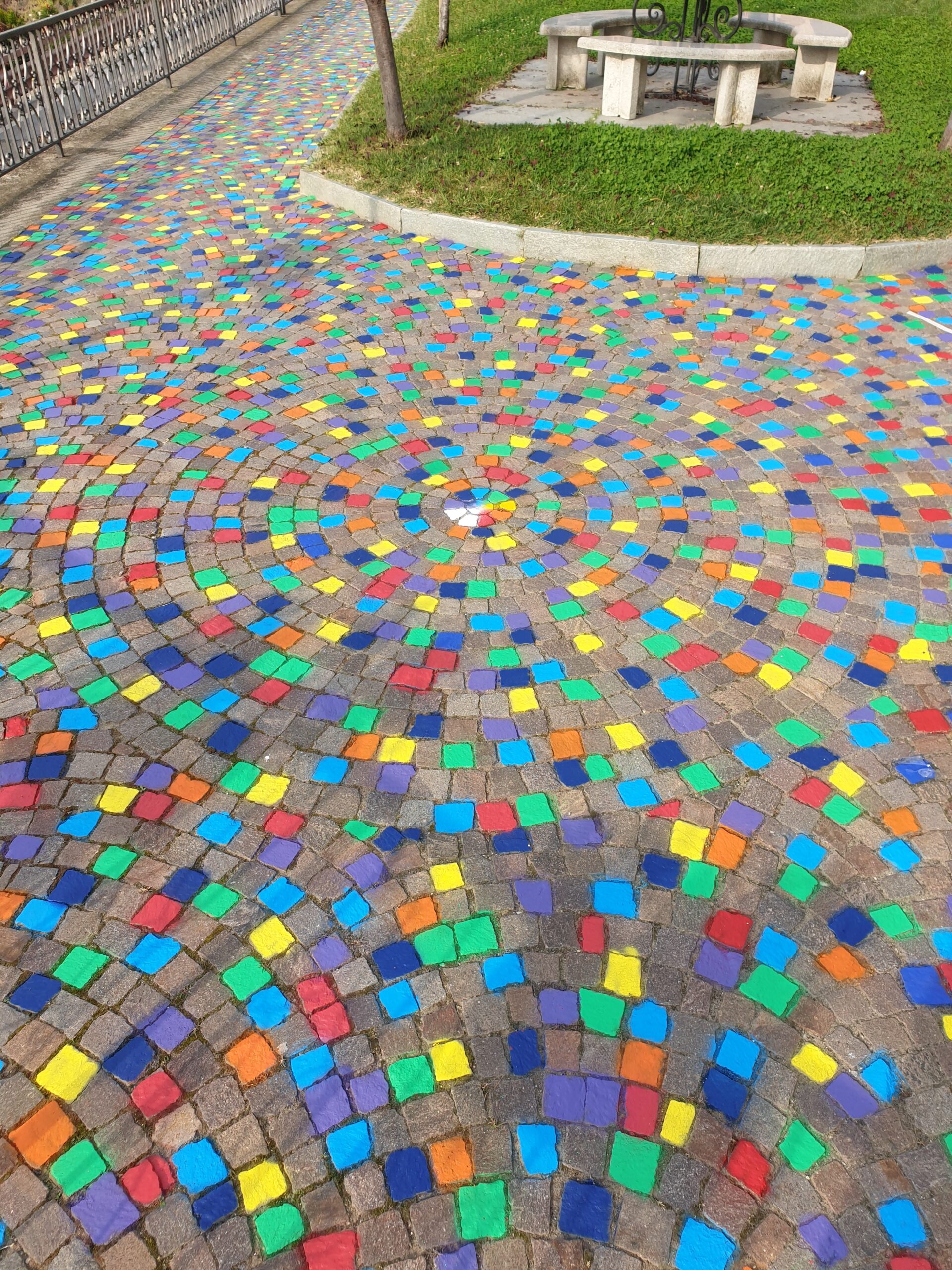 Opera di Land Art “Meditaçion” a Monticello d’Alba (CN), installazione di land art con sanpietrini colorati a spirale, percorso simbolico tra dimensione spirituale e materiale, arte ambientale contemporanea con geometrie circolari e colori vibranti.